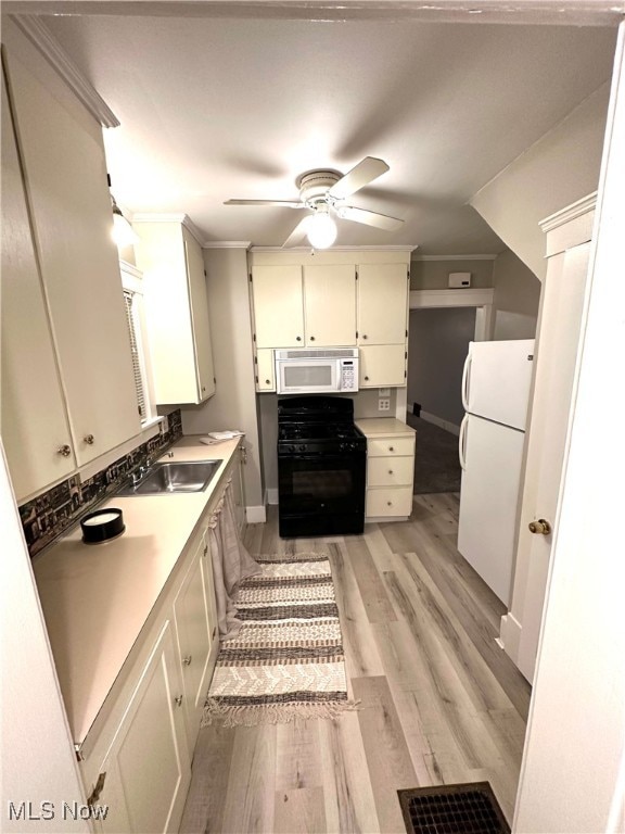 kitchen featuring sink, ornamental molding, ceiling fan, light wood-type flooring, and white appliances