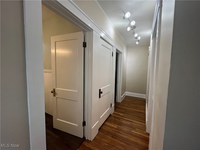 hallway featuring ornamental molding, track lighting, and dark hardwood / wood-style flooring