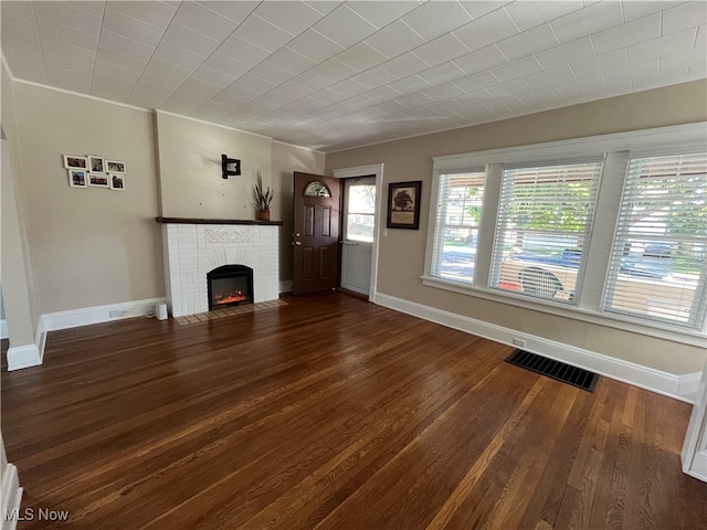 unfurnished living room featuring a brick fireplace and dark hardwood / wood-style flooring