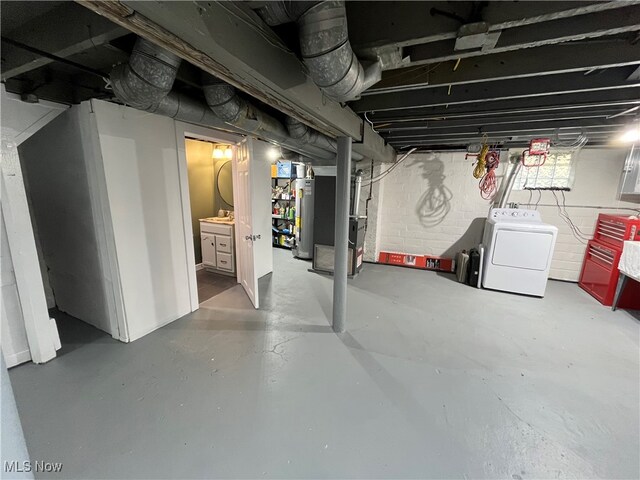 basement featuring water heater, washer / clothes dryer, and heating unit