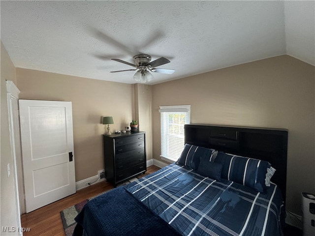 bedroom with a textured ceiling, dark hardwood / wood-style flooring, ceiling fan, and vaulted ceiling