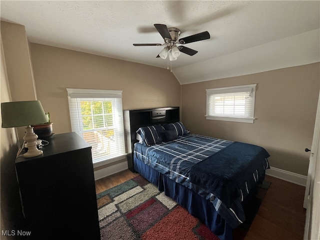 bedroom with dark wood-type flooring, multiple windows, lofted ceiling, and ceiling fan