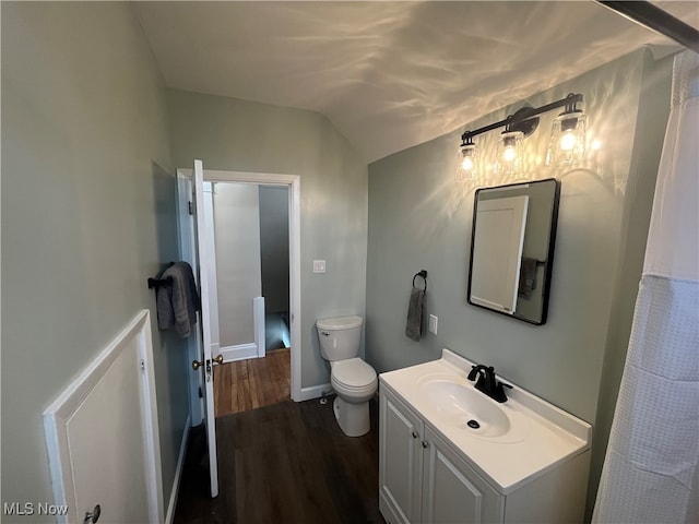 bathroom featuring toilet, vanity, wood-type flooring, and vaulted ceiling