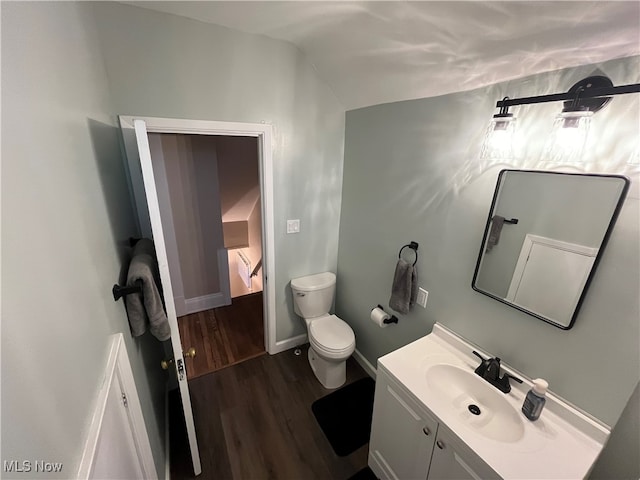 bathroom featuring hardwood / wood-style floors, vanity, toilet, and vaulted ceiling