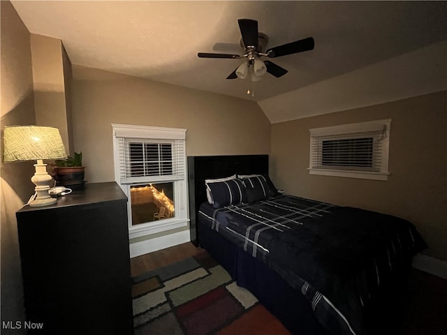 bedroom with dark hardwood / wood-style flooring, vaulted ceiling, and ceiling fan