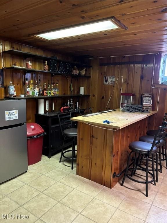 57365 Washington Blvd, Martins Ferry, OH 43935 - indoor bar featuring freestanding refrigerator, light tile patterned flooring, wood ceiling, and wooden walls