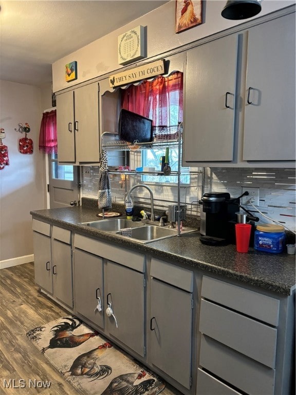 kitchen featuring dark wood-type flooring, gray cabinetry, tasteful backsplash, and sink