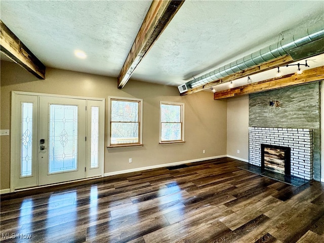 unfurnished living room featuring dark hardwood / wood-style floors, beam ceiling, and a tiled fireplace