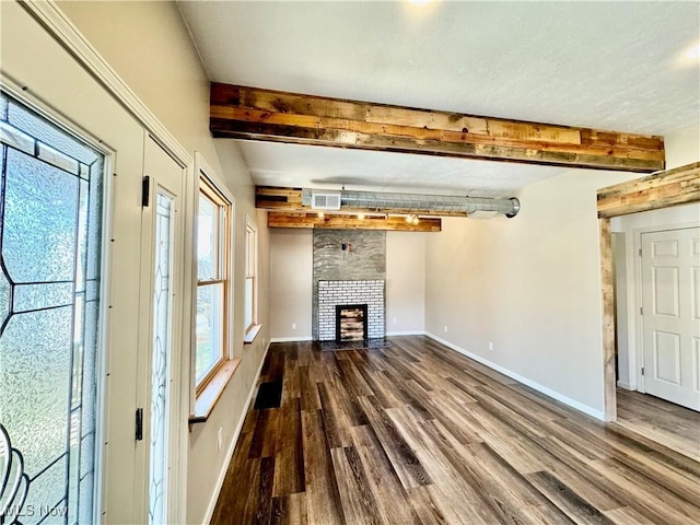 unfurnished living room with a fireplace, beamed ceiling, and wood-type flooring