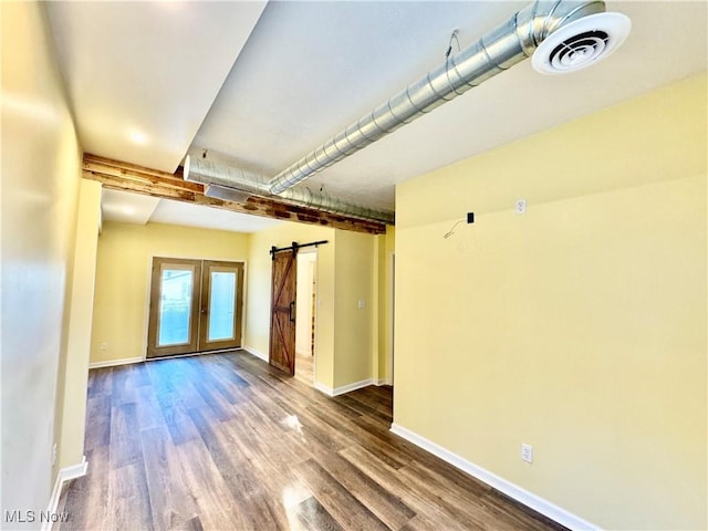 spare room featuring french doors, a barn door, and hardwood / wood-style flooring