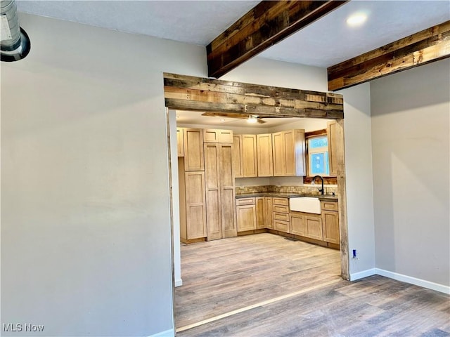 kitchen with light brown cabinets, beamed ceiling, light hardwood / wood-style floors, and sink