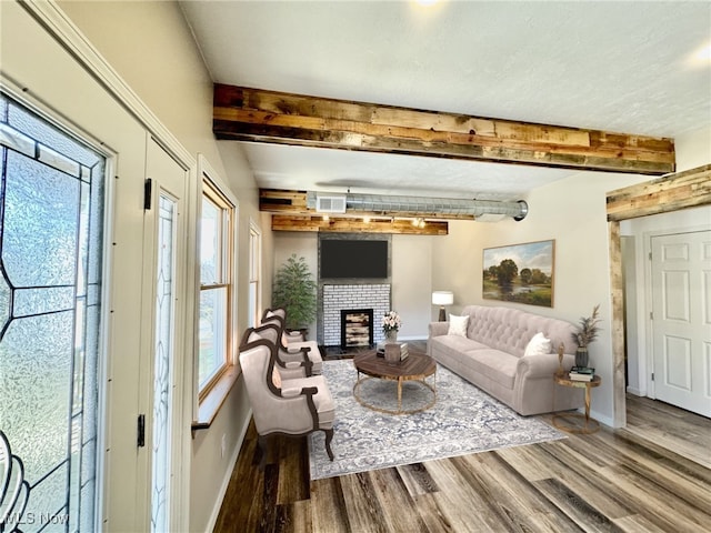 living room featuring beam ceiling, hardwood / wood-style floors, and a brick fireplace