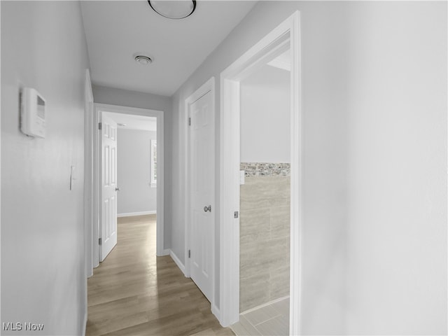 corridor featuring light hardwood / wood-style flooring and tile walls