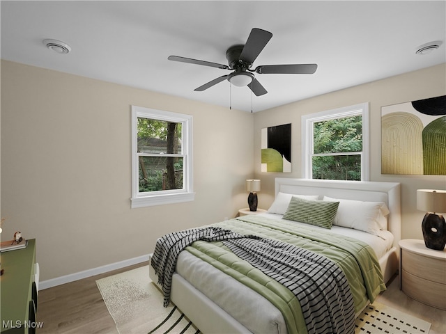 bedroom featuring multiple windows, wood-type flooring, and ceiling fan