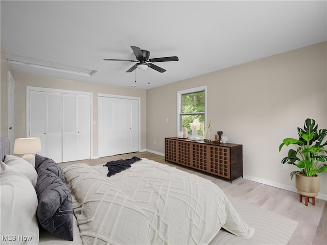 bedroom featuring two closets, hardwood / wood-style flooring, and ceiling fan