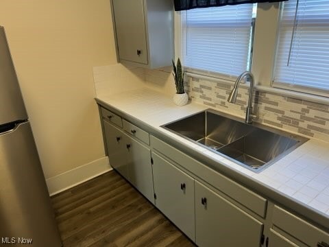 kitchen featuring dark wood-type flooring, decorative backsplash, sink, and stainless steel refrigerator