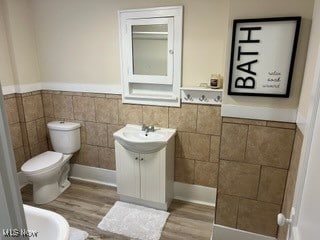 bathroom featuring tile walls, vanity, hardwood / wood-style flooring, and toilet