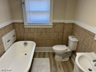 bathroom with wood-type flooring, toilet, and a bathtub