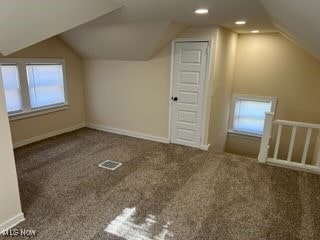 bonus room with lofted ceiling and dark carpet