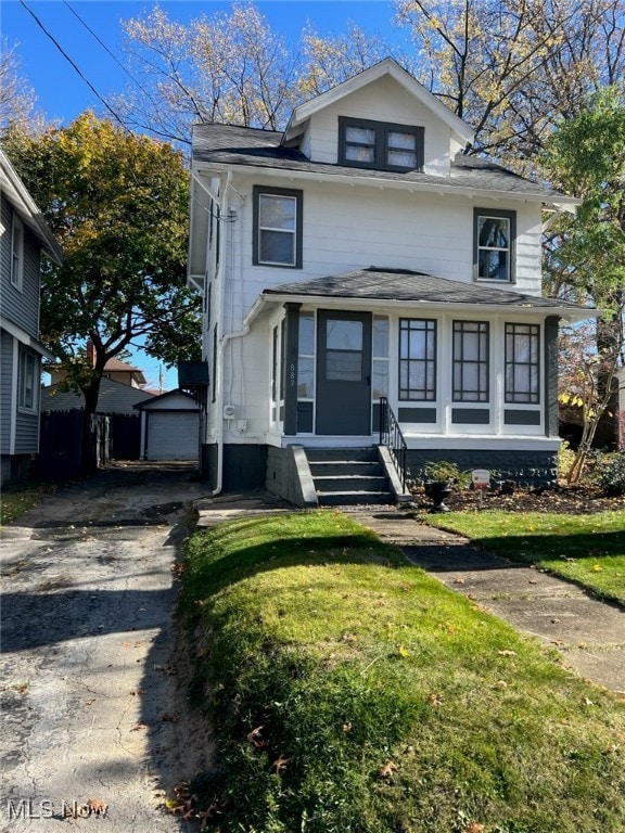 view of front of home featuring a front yard, a garage, and an outdoor structure