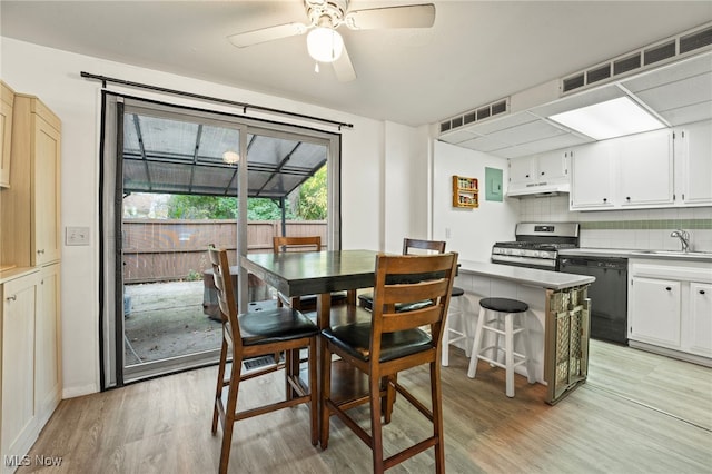 dining area with light wood-type flooring, sink, and ceiling fan