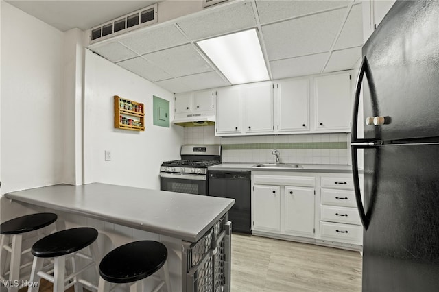 kitchen with white cabinets, decorative backsplash, black appliances, and sink