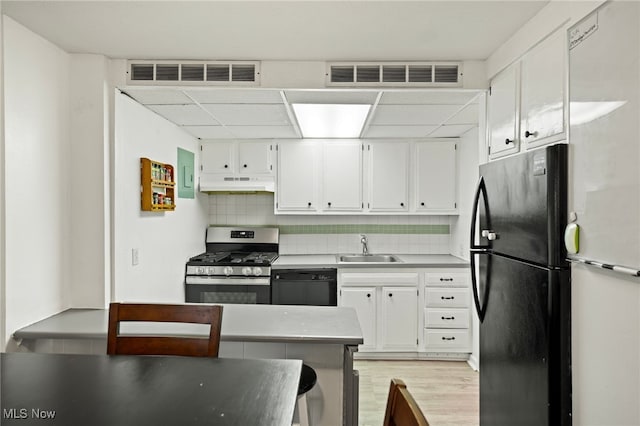 kitchen with light hardwood / wood-style floors, white cabinetry, sink, black appliances, and decorative backsplash