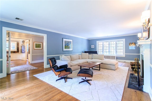 living room with ornamental molding and light hardwood / wood-style flooring