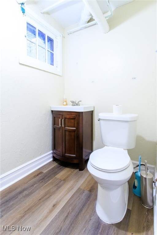 bathroom with wood-type flooring, vanity, and toilet