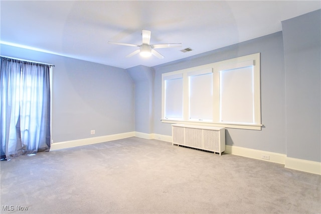 carpeted spare room featuring ceiling fan and radiator