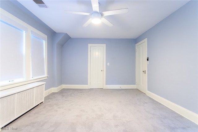 bonus room featuring radiator, ceiling fan, and light carpet