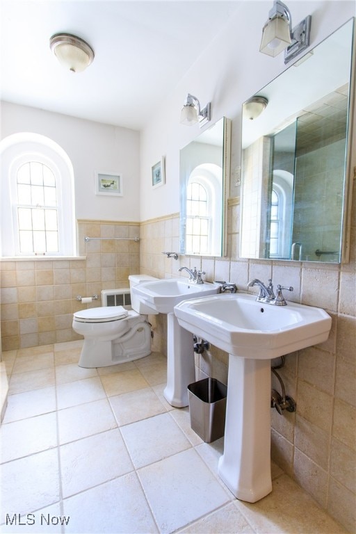 bathroom with tile walls, dual sinks, and tile patterned floors