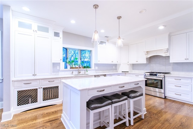 kitchen featuring wood-type flooring, a kitchen island, white cabinetry, custom range hood, and stainless steel range with gas stovetop