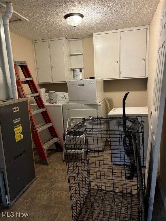 laundry area featuring a textured ceiling, cabinets, and washer and dryer