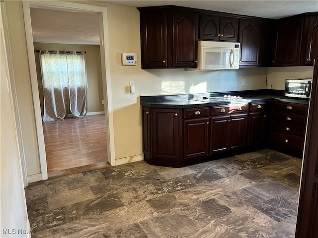 kitchen featuring gas cooktop, a textured ceiling, dark brown cabinetry, and dark hardwood / wood-style floors