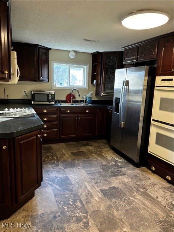 kitchen featuring appliances with stainless steel finishes, sink, dark brown cabinets, and a textured ceiling