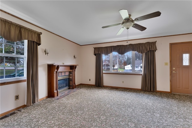 unfurnished living room with ceiling fan, a wealth of natural light, carpet flooring, and ornamental molding