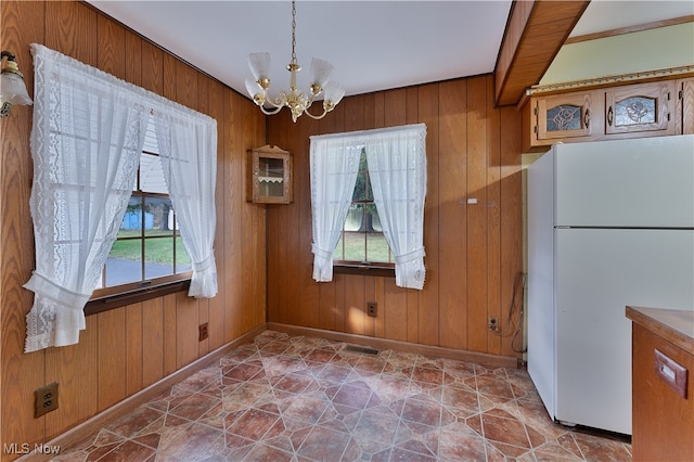 unfurnished dining area featuring wood walls and a notable chandelier