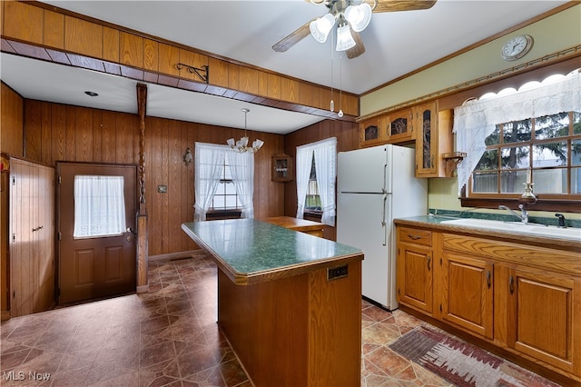 kitchen featuring a wealth of natural light, a kitchen island, white refrigerator, and wooden walls