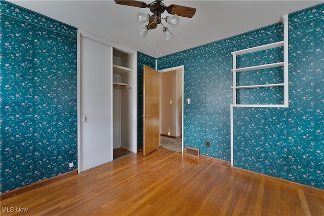 unfurnished bedroom with wood-type flooring, ceiling fan, and a closet