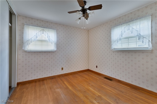 spare room featuring wood-type flooring, a healthy amount of sunlight, and ceiling fan