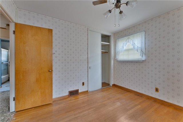 unfurnished bedroom with a closet, wood-type flooring, and ceiling fan