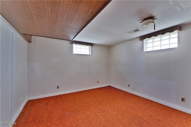 basement featuring wooden ceiling, a healthy amount of sunlight, and carpet