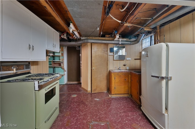 kitchen with wood walls, white appliances, and white cabinetry