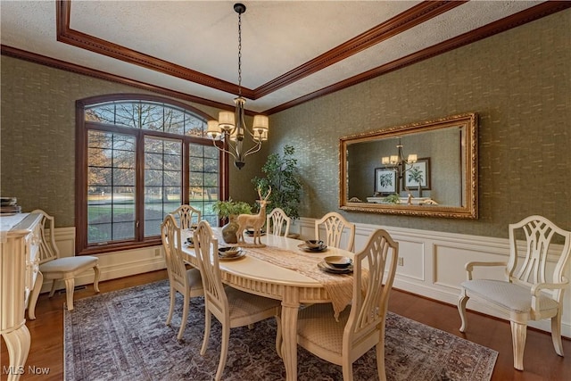 dining area featuring hardwood / wood-style flooring, a raised ceiling, crown molding, and a chandelier