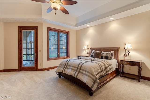 bedroom featuring a tray ceiling, ceiling fan, and light carpet