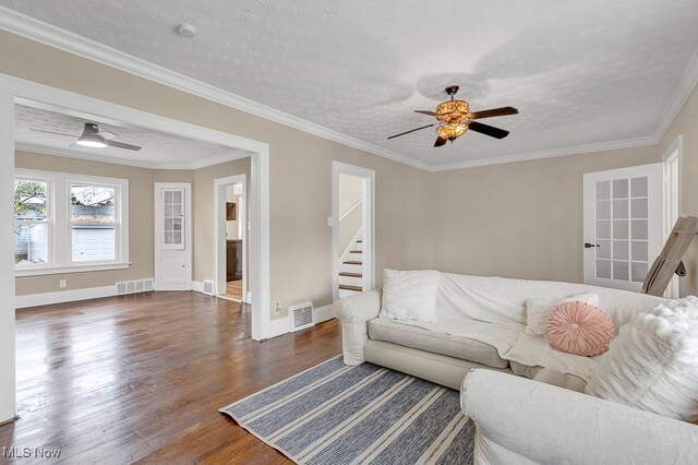 living room with dark hardwood / wood-style flooring, a textured ceiling, ceiling fan, and crown molding