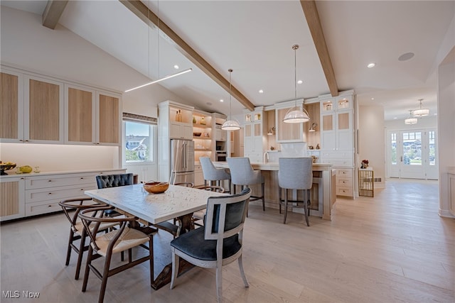 dining room with lofted ceiling with beams, plenty of natural light, and light hardwood / wood-style flooring