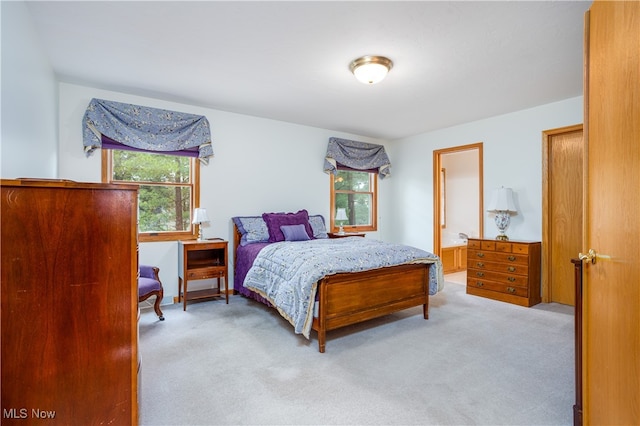 bedroom featuring ensuite bathroom and light carpet