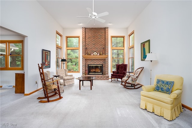 living area with carpet flooring, ceiling fan, and a brick fireplace